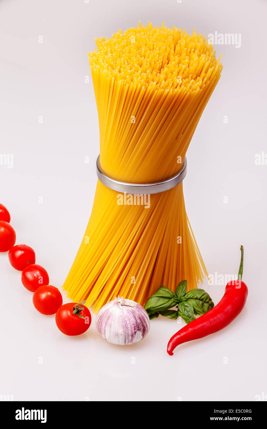 Spaghetti standing with fresh spices and vegetables, raw Stock Photo