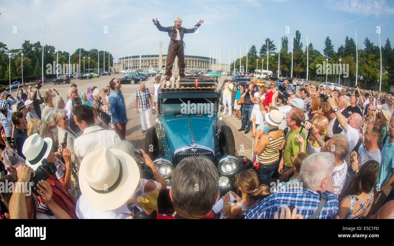 Berlin, Germany. 27th July, 2014. The former racing driver Heidi Hetzer stands on the roof of her classic car and speaks to curious onlookers in front of the Olympic stadium in Berlin, Germany, 27 July 2014. Hetzer starts her world trip from Berlin in her Hudson Great Eight classic car, a 1930 model. Photo: Hannibal/dpa/Alamy Live News Stock Photo