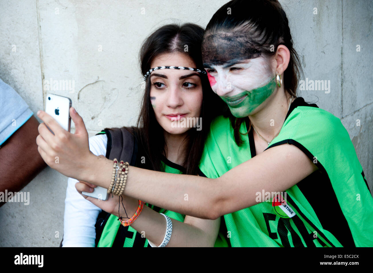 Demonstration against Israeli bombing of Gaza,Taking a selfie. Young women with faces painted in the colours of Palestinian flag Stock Photo