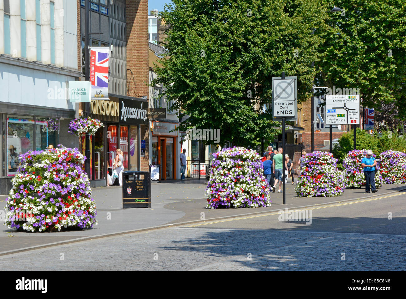 High street shopping area with pavement floral decorations provided by local borough council Stock Photo