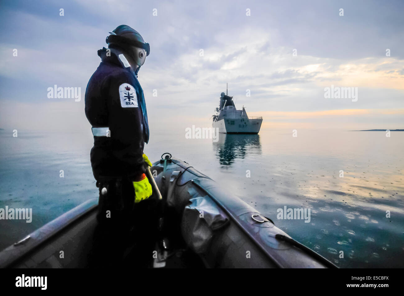 Belfast, Northern Ireland. 26/07/2014 - A Royal Navy sailor stands at the prow of a Pacific 28 RIB as it approaches HMS Duncan. Stock Photo