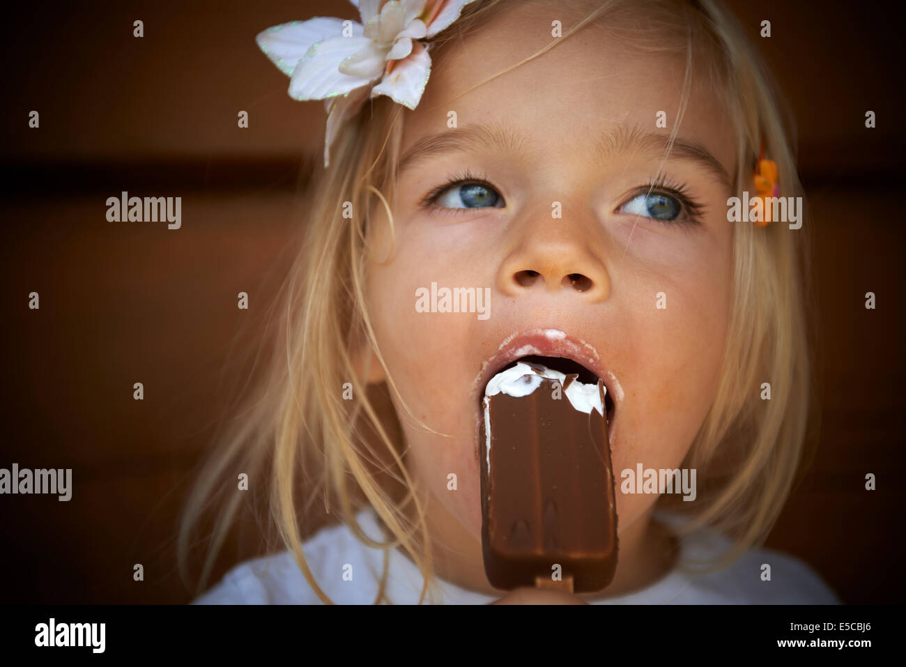 Little child blond girl licking an ice cream, portrait, lying green lawn  grass background Stock Photo - Alamy