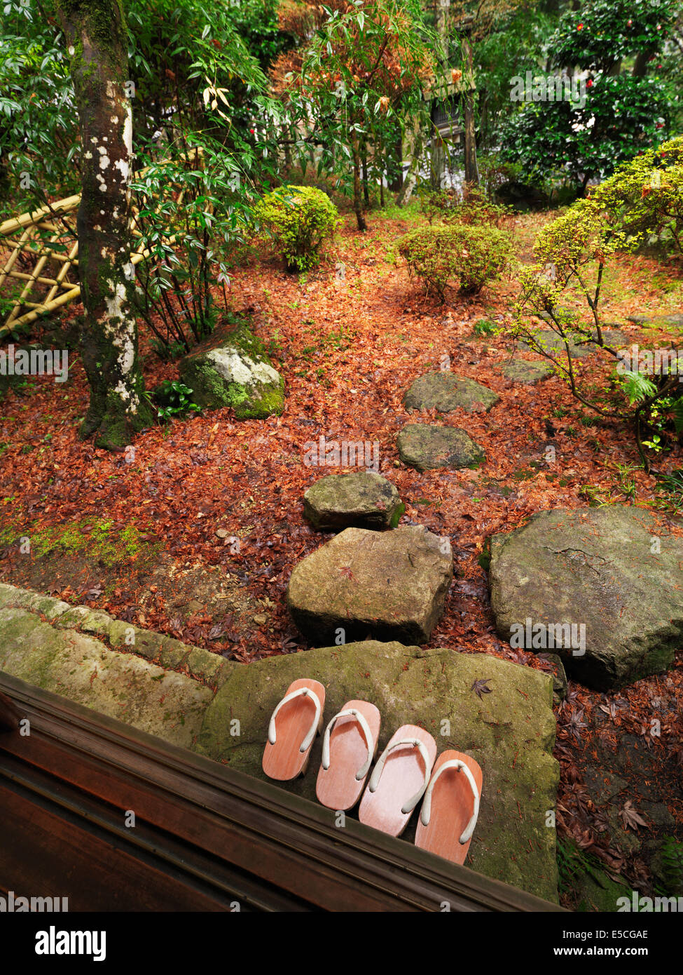 Geta shoes outside a ryokan room with a Japanese garden after a rain. Gero, Japan. Stock Photo