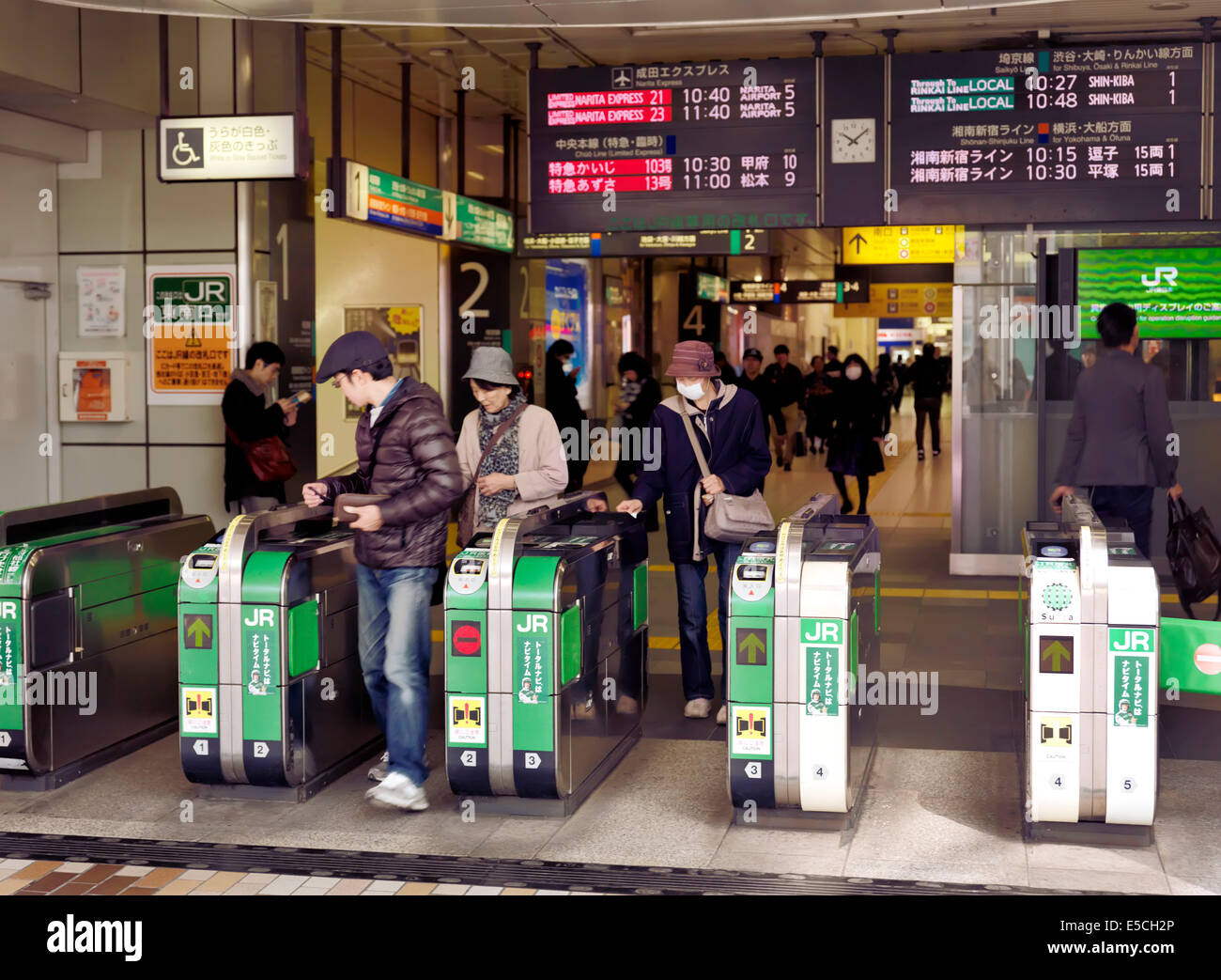 People passing through JR train station turnstiles. Tokyo, Japan Stock Photo