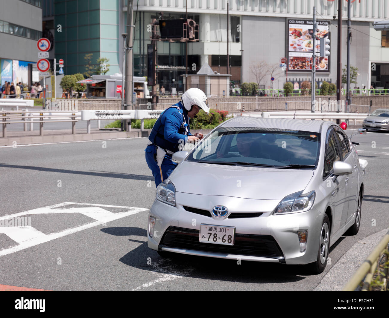 Police officer checking a drivers license of a driver in a stopped car. Tokyo, Japan. Stock Photo