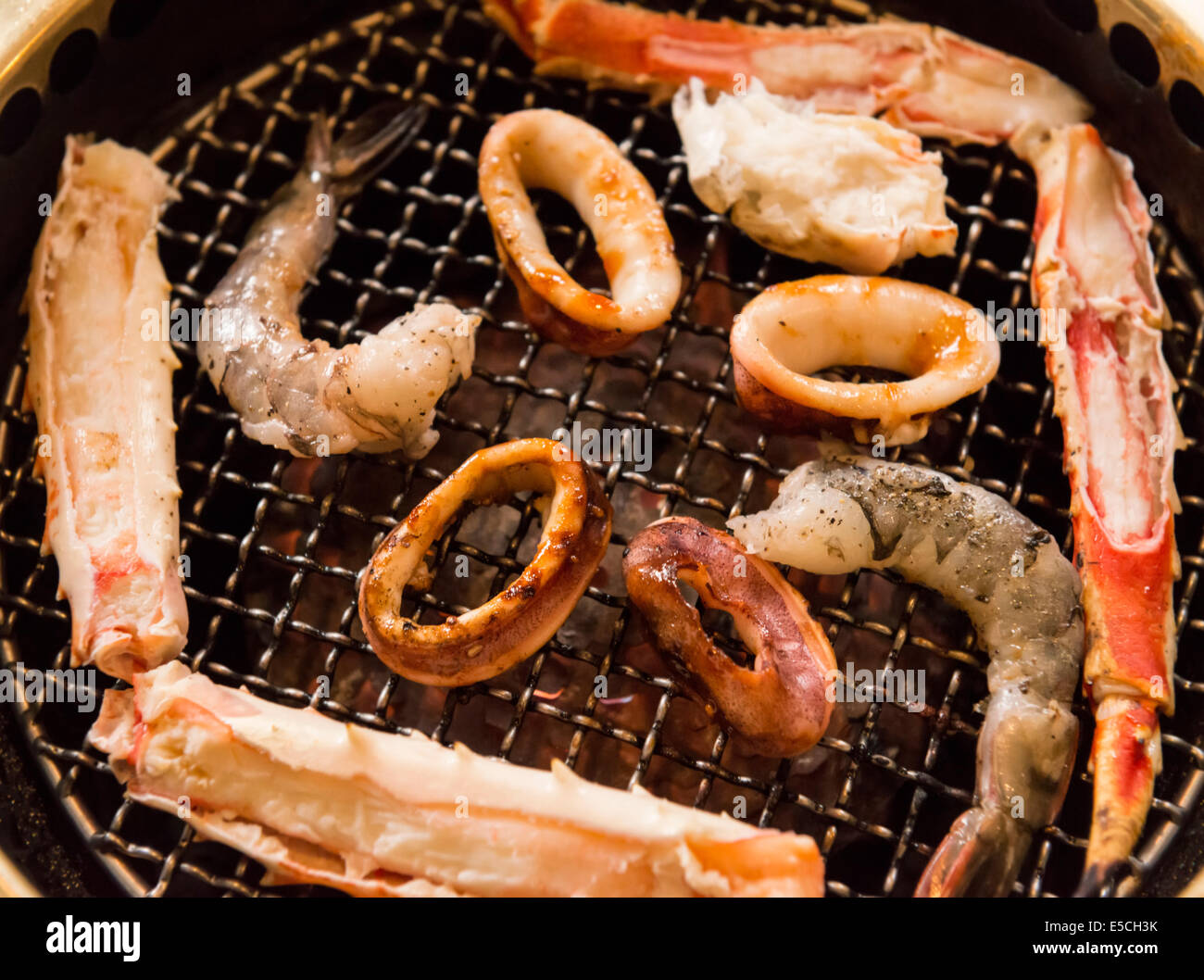 Closeup of seafood being cooked on a Japanese grill stove at a restaurant Stock Photo