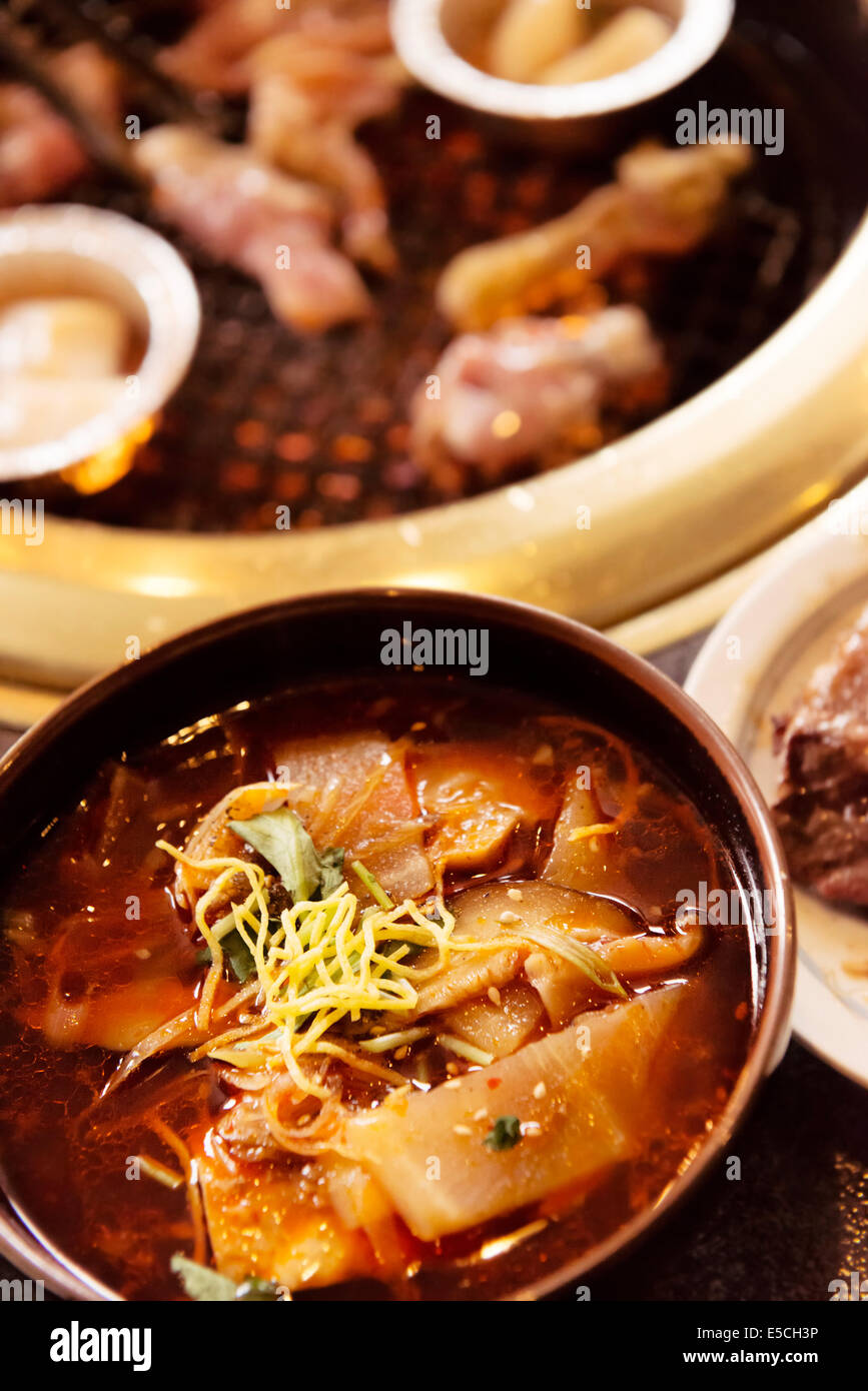 Closeup of a bowl of soup and beef being cooked on fire at a Japanese grill restaurant Stock Photo