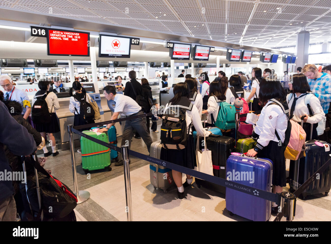 Japanese schoolgirls lined up at Air Canada check-in counter of Narita International Airport in Japan Stock Photo