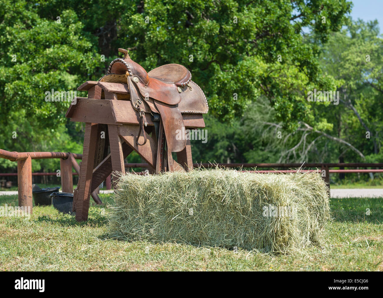 Leather horse saddle displayed on a wooden stand and a hay bale Stock Photo