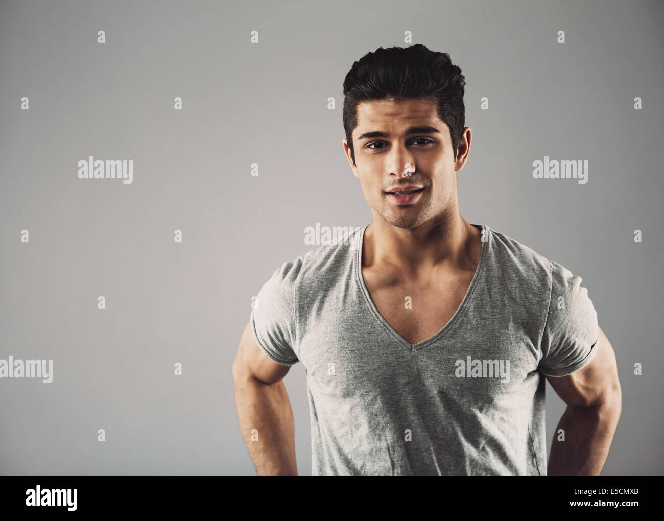 Portrait of confident young hispanic male fashion model posing against grey background with copy space. Stock Photo