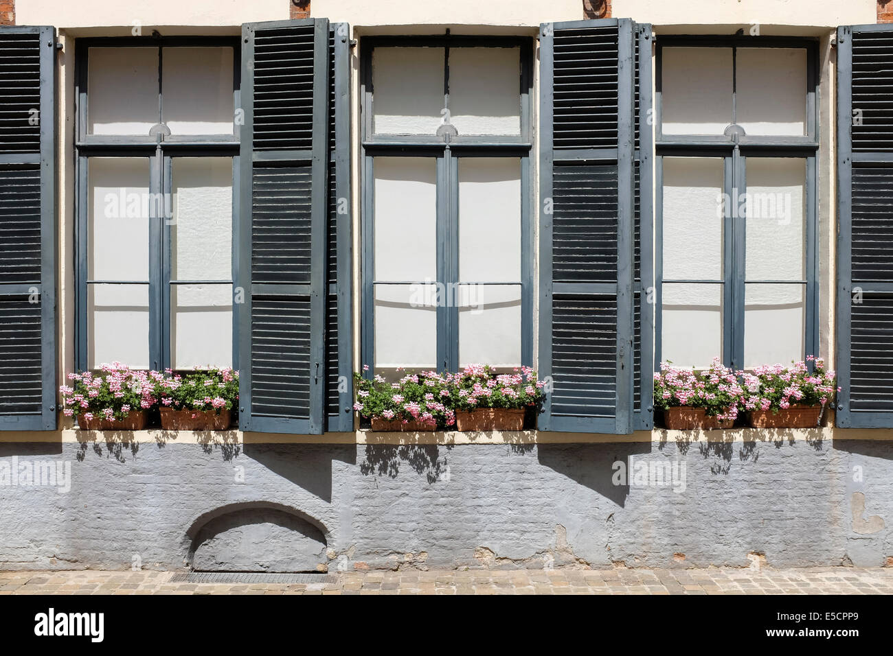 Flowerpots on the windows of a house in Bruges old town, Belgium Stock Photo