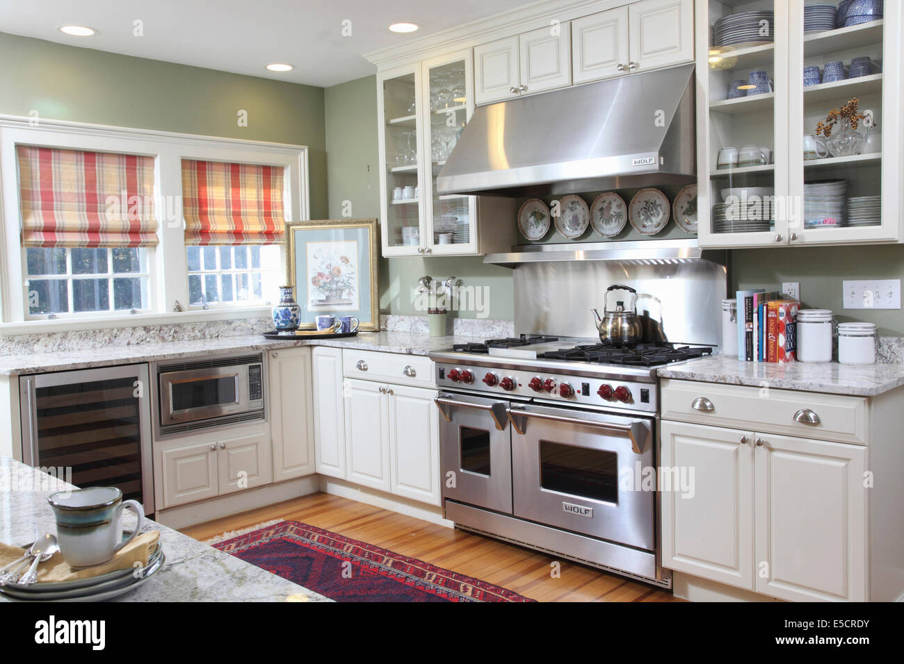 Bright white kitchen with large stainless steel gas range and hood