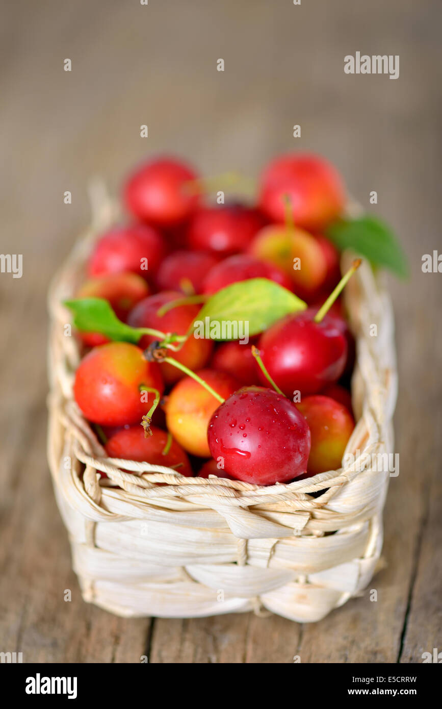 cherry-plum in basket on wooden background Stock Photo