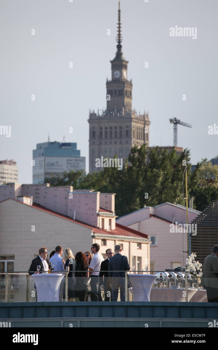 Guests at a wedding in Poland taking place on the rooftop of a building. The Palace of Science and Culture is in the distance Stock Photo