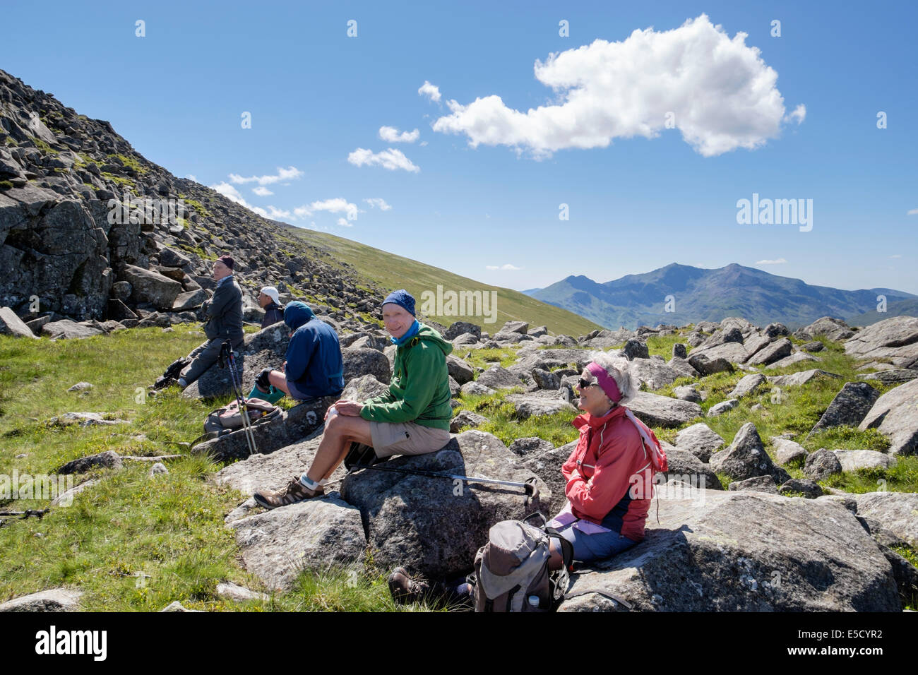Ramblers hikers resting on rocks on Moel Siabod with view to Snowdon in mountains of Snowdonia National Park Conwy North Wales UK Stock Photo