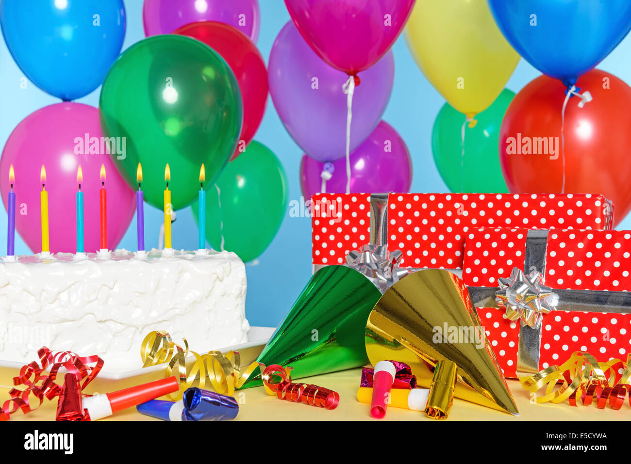 Birthday party still life with cake, balloons, presents, streamers and hats. Stock Photo
