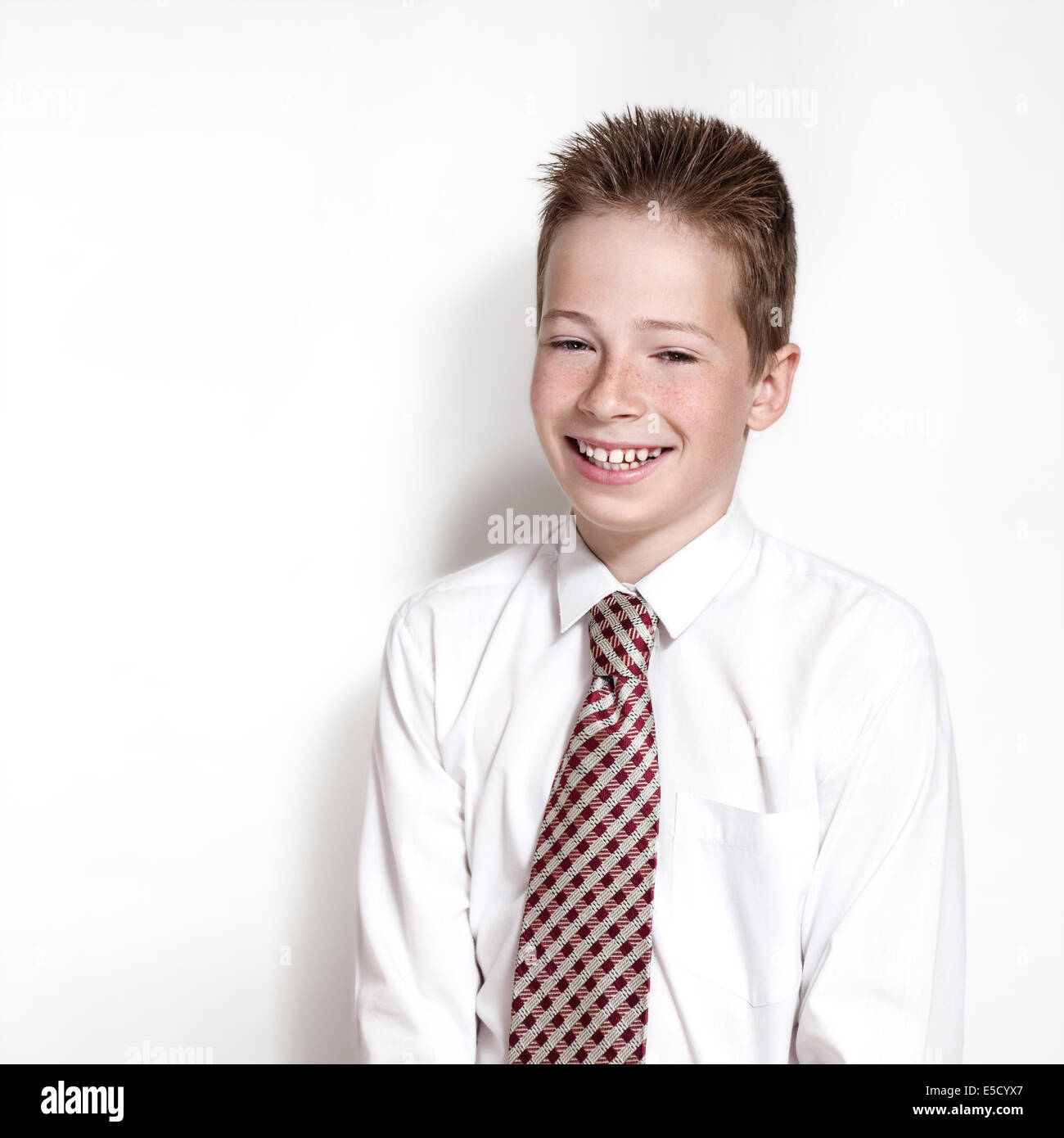 The nice smiling boy teenager in a white shirt and a tie on a gray background with place for text Stock Photo