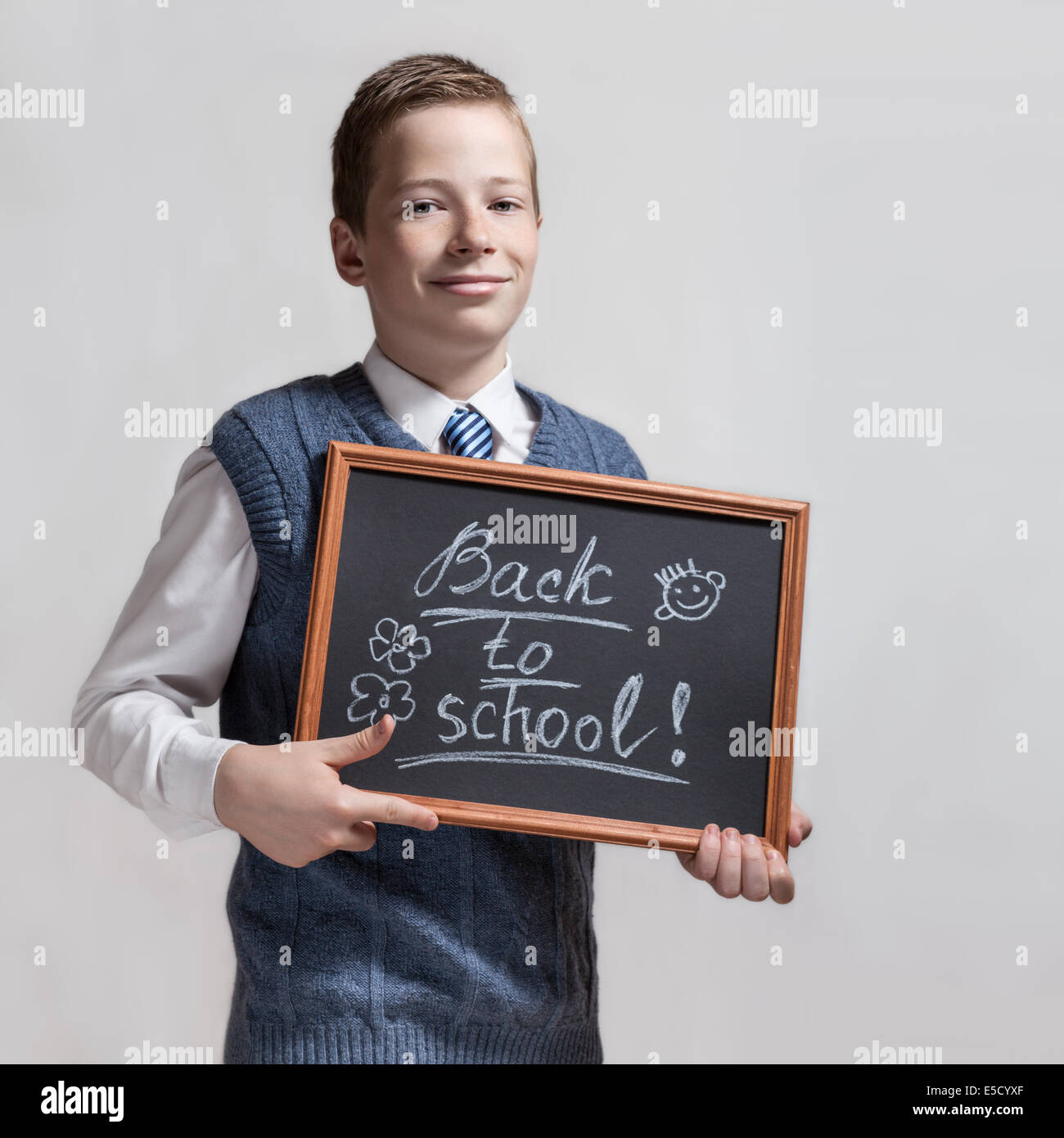 The cute smart schoolboy teenager shows the black chalkboard with the inscription - back to school Stock Photo