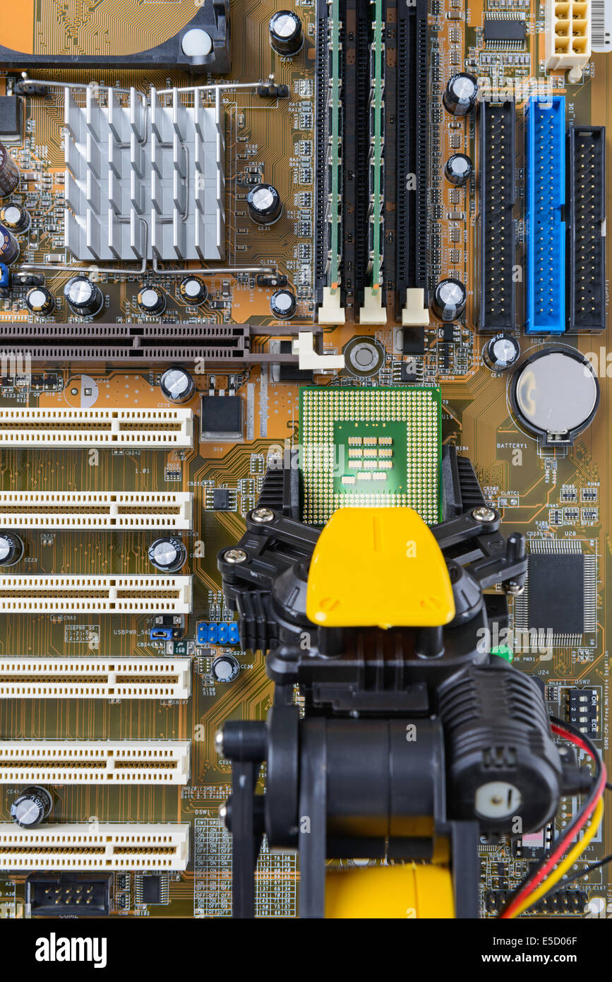 Robotic arm installing a computer chip on a motherboard. Stock Photo