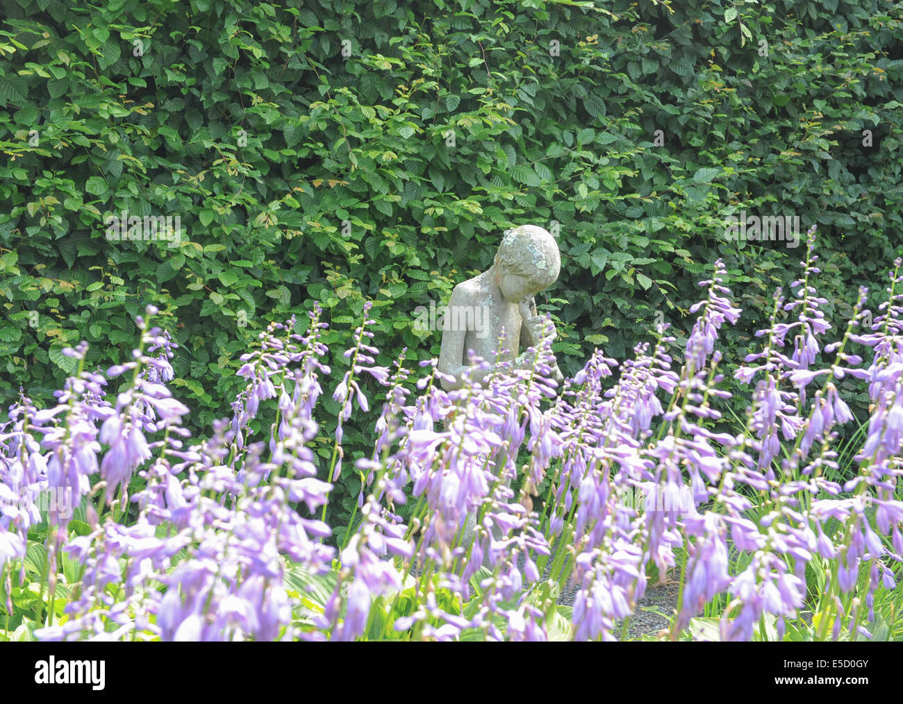 Statue of young male playing a musical instrument in the gardens at