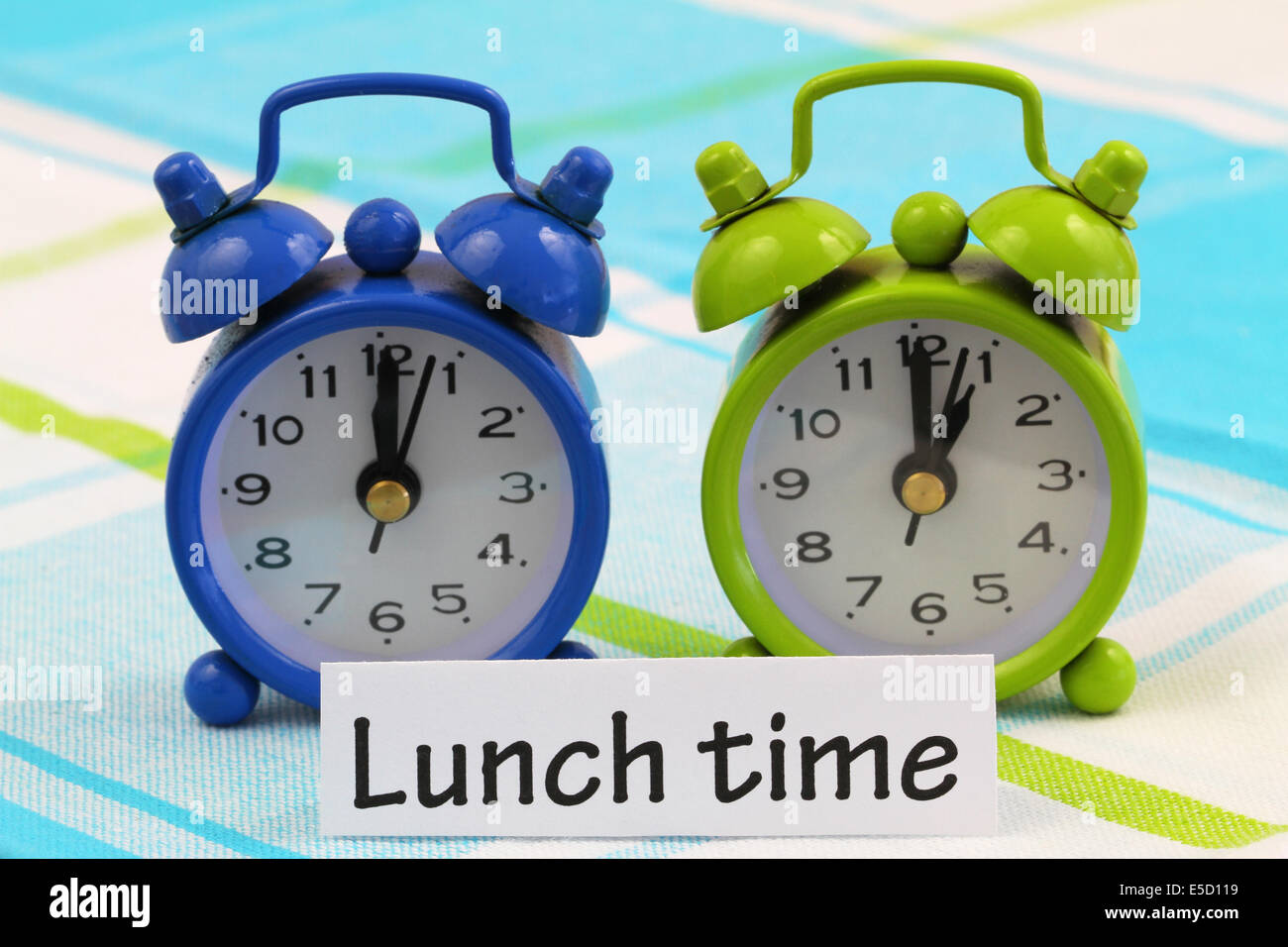 Lunch time card with two miniature clocks showing twelve and one o'clock Stock Photo