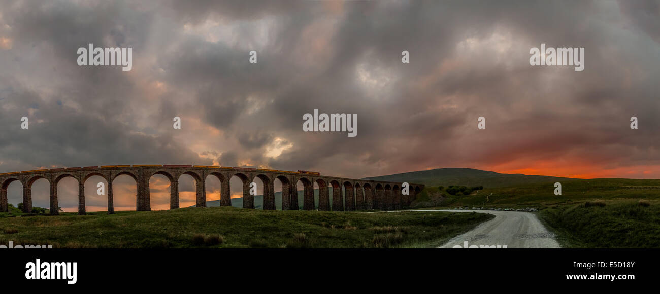 creative scene of the rural Ribblehead viaduct in a quite remarkable sunset with a train crossing, Yorkshire Dales, England, UK Stock Photo