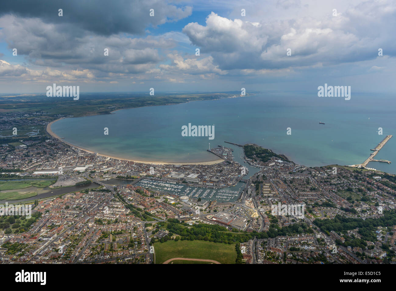 A wide aerial view of the Dorset town of Weymouth with the nearby coastline and countryside visible amd a dramatic sky. Stock Photo