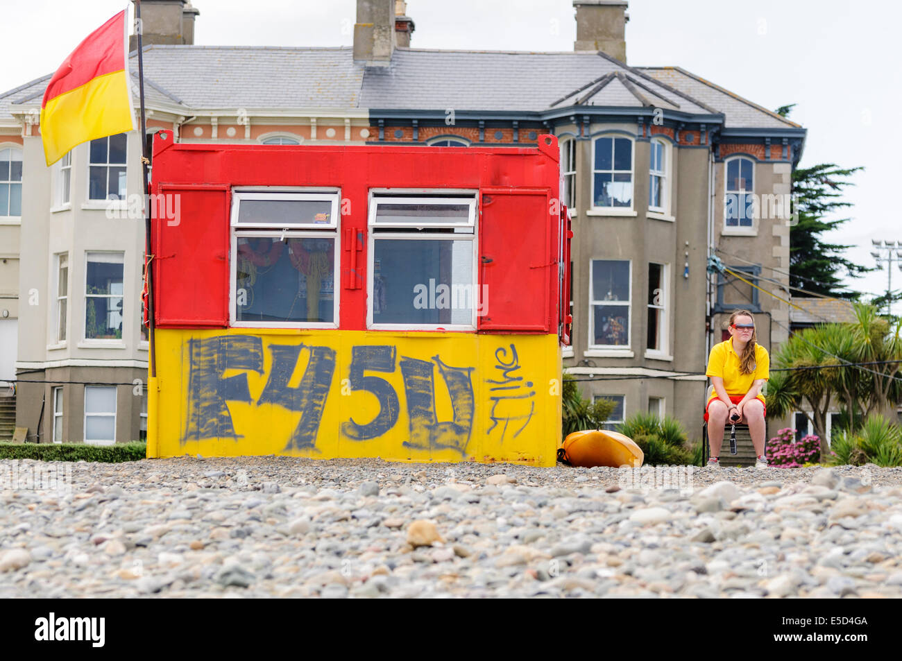 Female life guard on duty beside a hut with graffiti at Bray Strand, County Wicklow Ireland Stock Photo