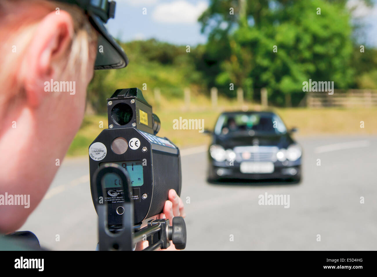 Female police officer uses a laser speed gun to detect a speeding car