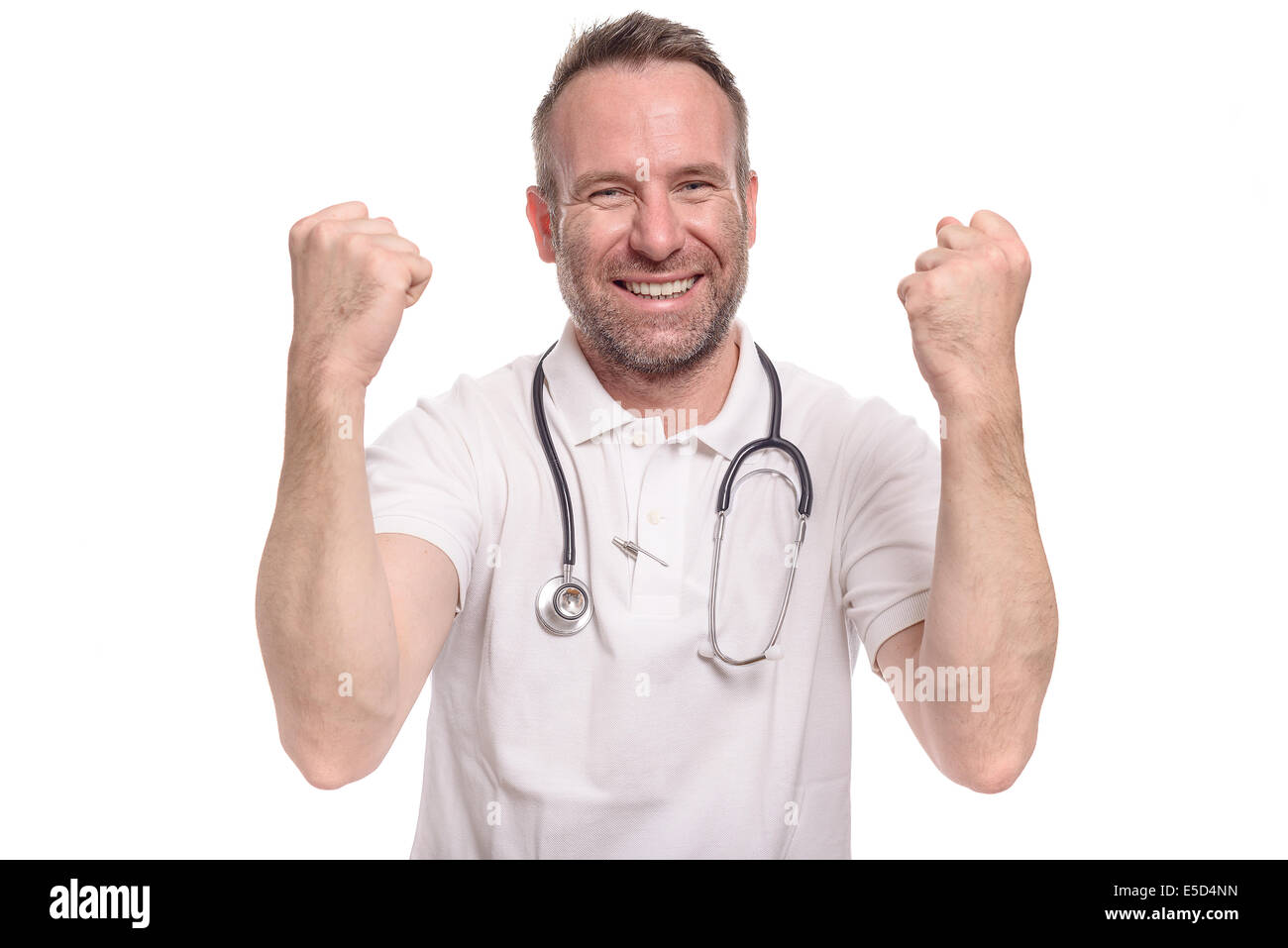 Enthusiastic unshaven middle-aged doctor punching the air with his fist celebrating a successful treatment or prognosis with a l Stock Photo