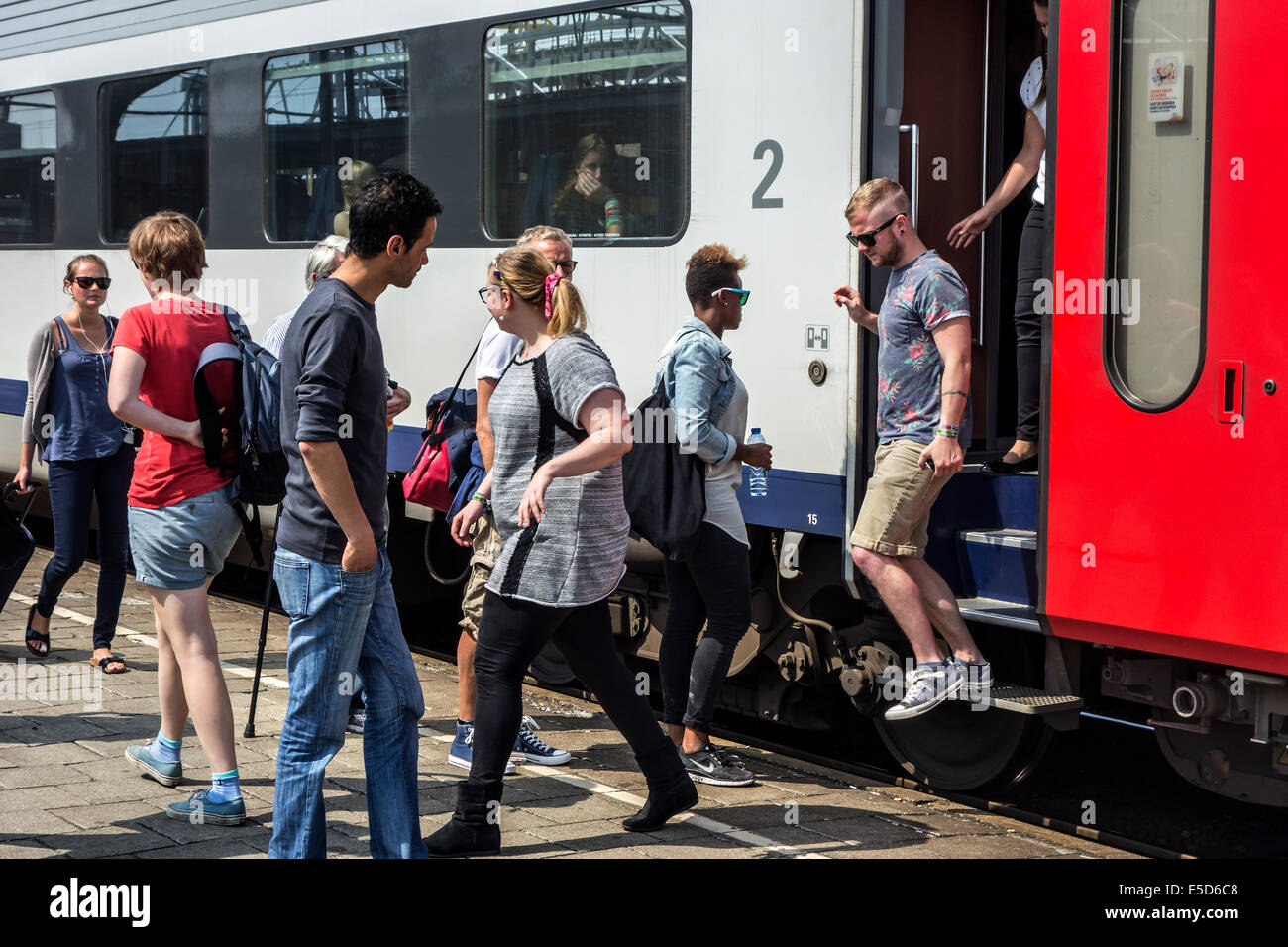 Passengers and commuters boarding passenger train on platform in railroad station Stock Photo