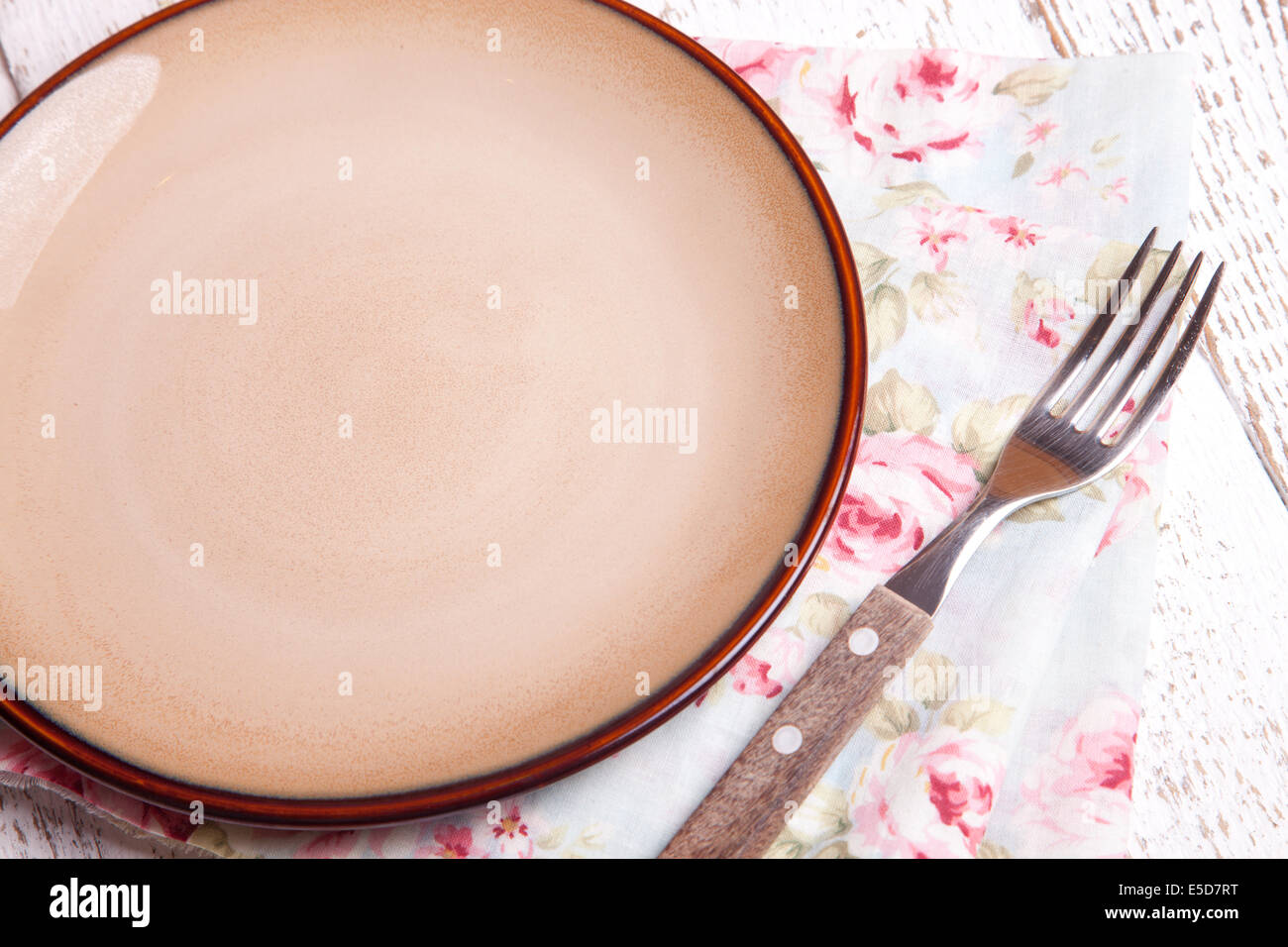 empty clay plate and fork on wooden table Stock Photo