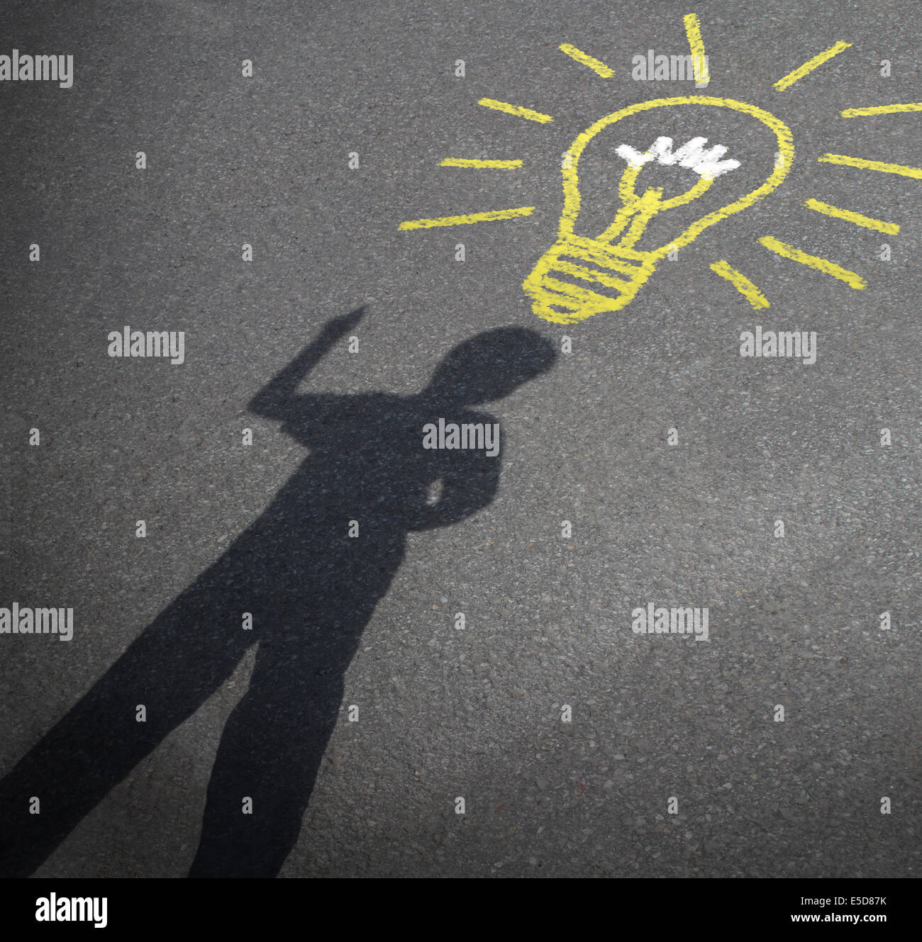 Childhood imagination and child creativity concept as the shadow of an inspired boy with a lightbulb chalk drawing on city asphalt as a symbol of inspiration and creative learning or back to school ideas. Stock Photo