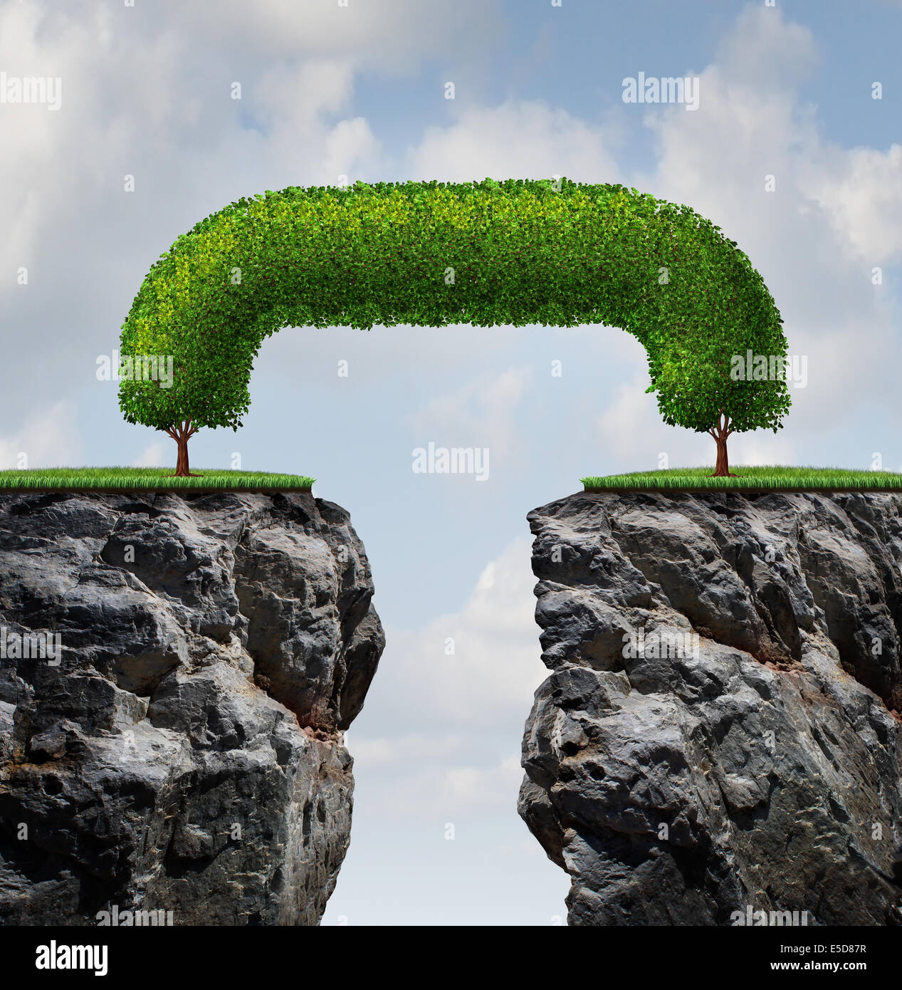 Bridge the gap business concept as two trees on a high steep cliff leaning towards each other bridging together to form a mutual Stock Photo