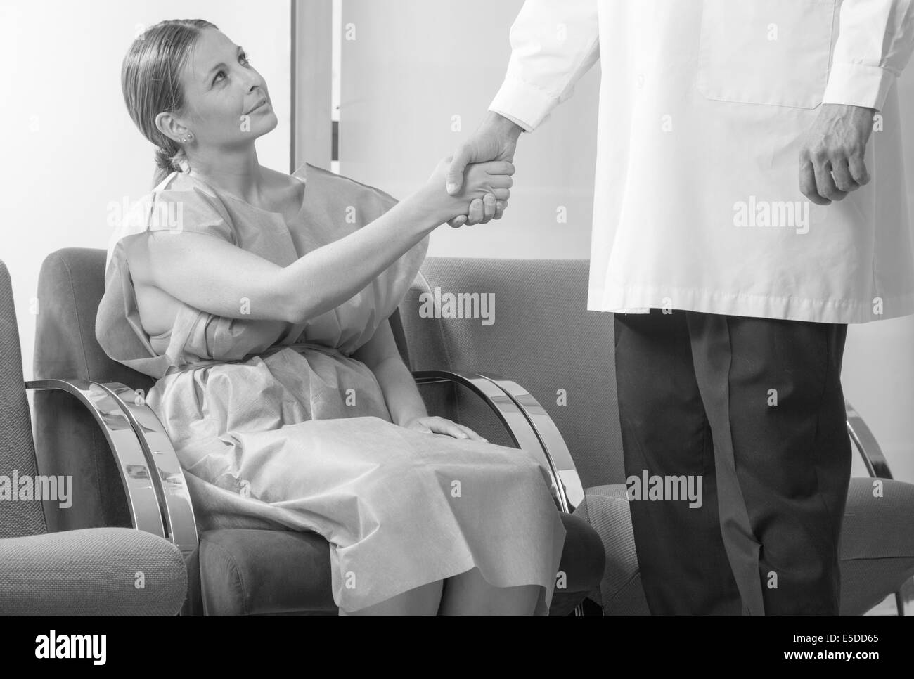 Woman patient in 40s shaking hand with doctor in hospital waiting room before checkup. Stock Photo