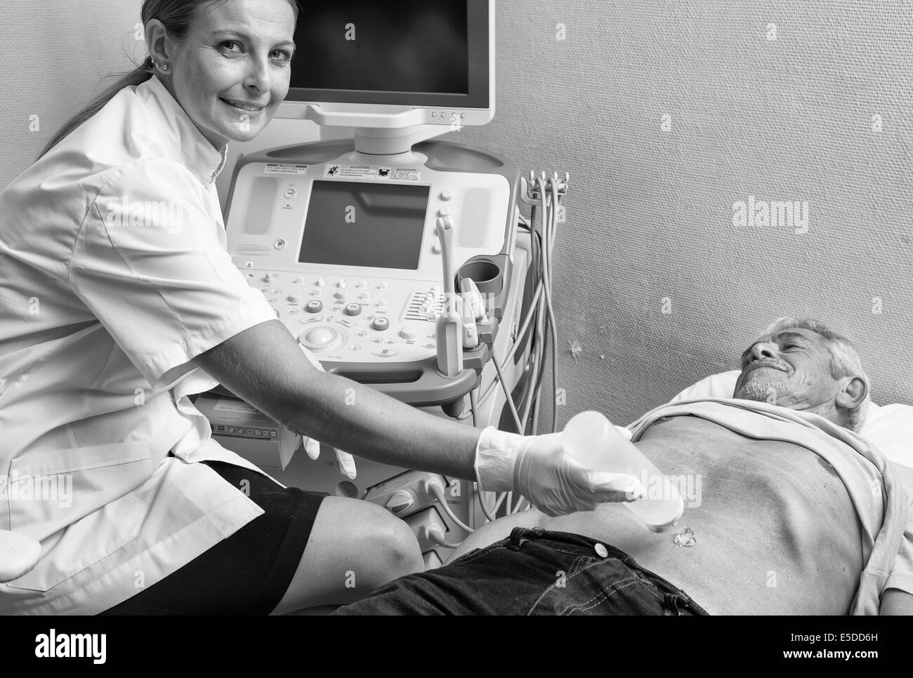 Happy woman doctor analyzing male patient with abdomen ultrasound. Stock Photo