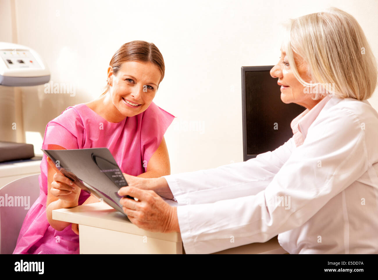 Happy doctor and female patient looking at medical scan results. Stock Photo