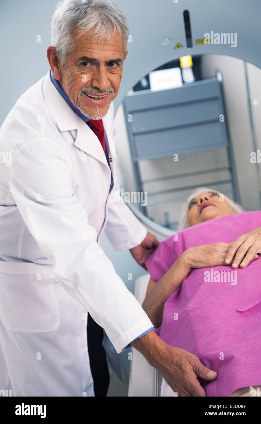 Smiling senior male doctor with female patient in 60s undergoing mri scan. Stock Photo