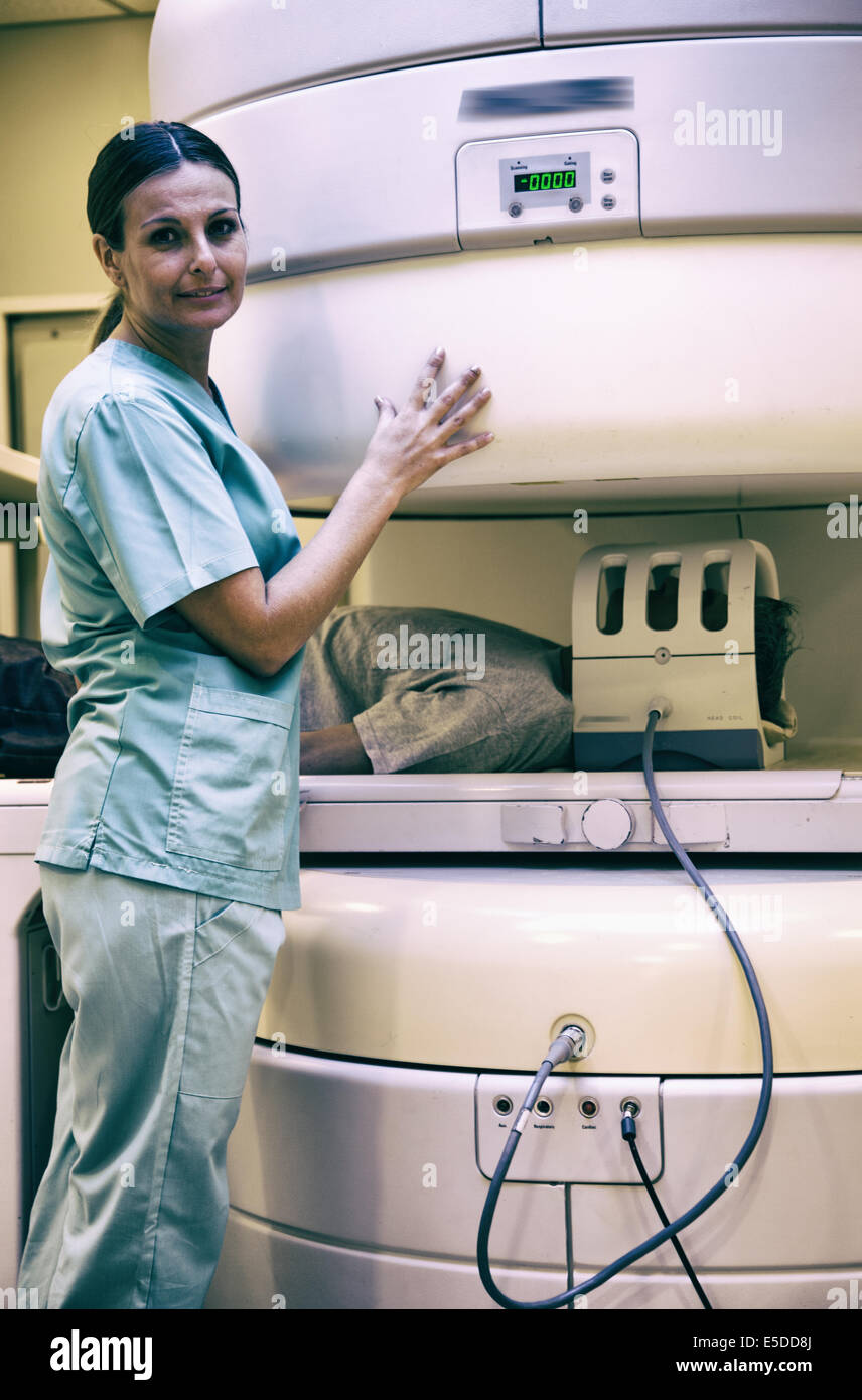 Male in 40s undergoing mri scan in open scanner with young female doctor smiling. Stock Photo
