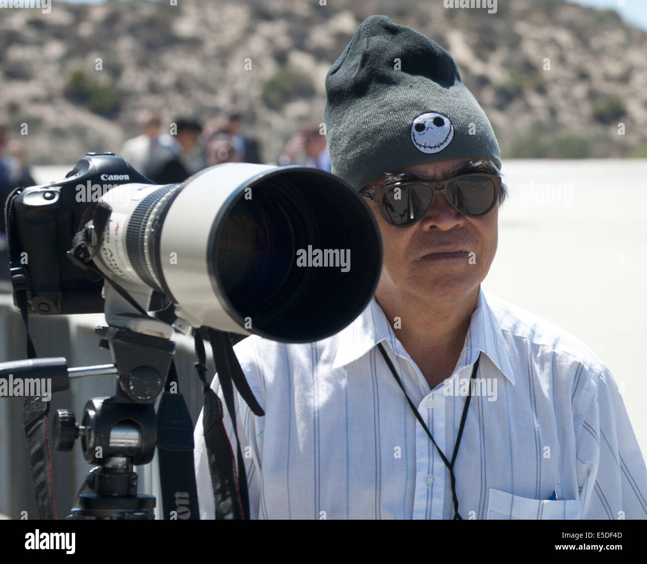 Los Angeles, California, USA. 23rd July, 2014. Pulitzer prize winning photojournalist Nick Ut stands by at Los Angeles International Airport as he waits for the arrival of Air Force One carrying US President Barack Obama. Ut set up his Cannon camera equipment along with about two dozen members of the media in a press pen in order to capture Obama disembarking Air Force One and boarding Marine One as part of a DNC fundraising trip. AP photographer Ut took his Pulitzer winning photograph, ''Napalm Girl, ' on June 8, 1972 along a road in Trang Bang, Vietnam. The black and white photo depicts a Stock Photo