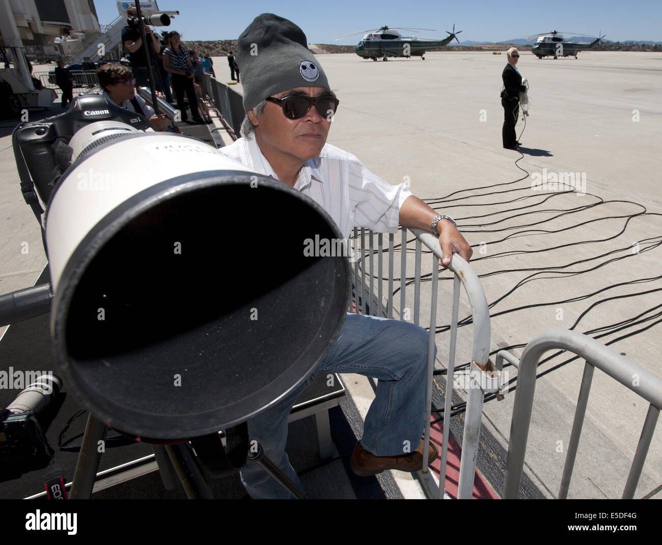 Los Angeles, California, USA. 23rd July, 2014. Pulitzer prize winning photojournalist Nick Ut stands by at Los Angeles International Airport as he waits for the arrival of Air Force One carrying US President Barack Obama. Ut set up his Cannon camera equipment along with about two dozen members of the media in a press pen in order to capture Obama disembarking Air Force One and boarding Marine One as part of a DNC fundraising trip. AP photographer Ut took his Pulitzer winning photograph, ''Napalm Girl, ' on June 8, 1972 along a road in Trang Bang, Vietnam. The black and white photo depicts a Stock Photo