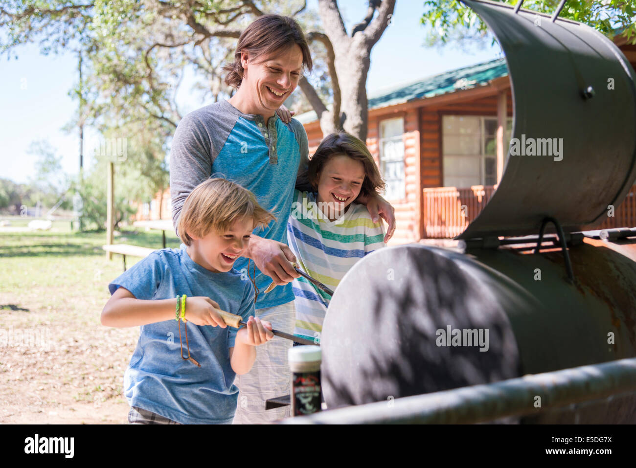 USA, Texas, Father with two sons having fun at barbecue Stock Photo