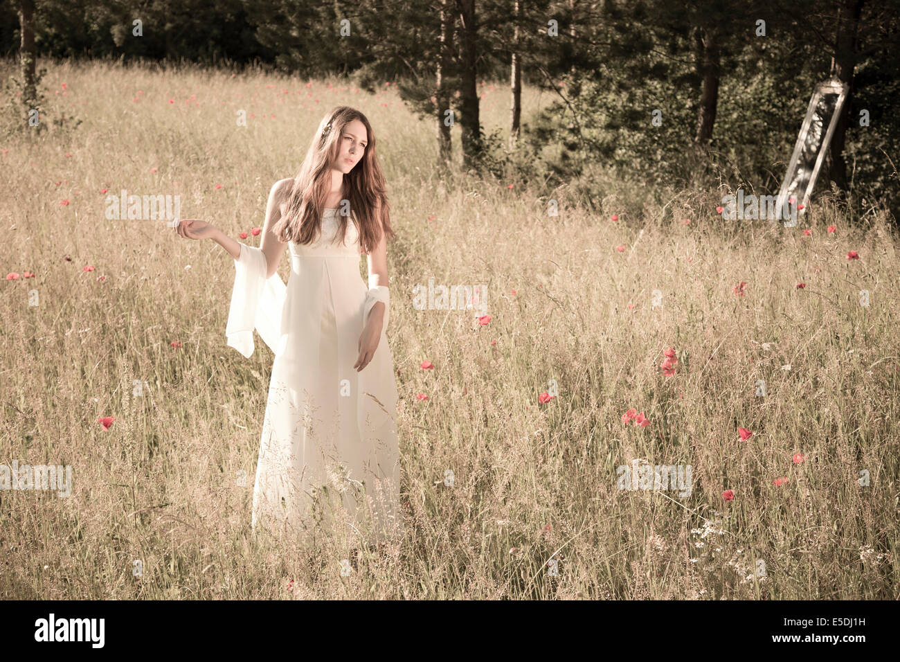 Portrait of teenage girl wearing white dress standing on meadow at ...