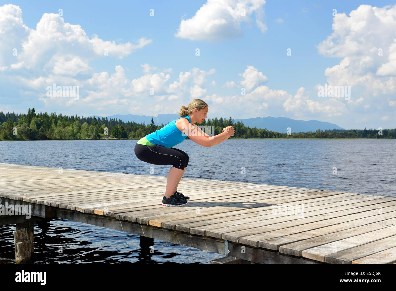 Germany, Bavaria, Sachsenkam, woman exercising functional training on jetty at sea Stock Photo