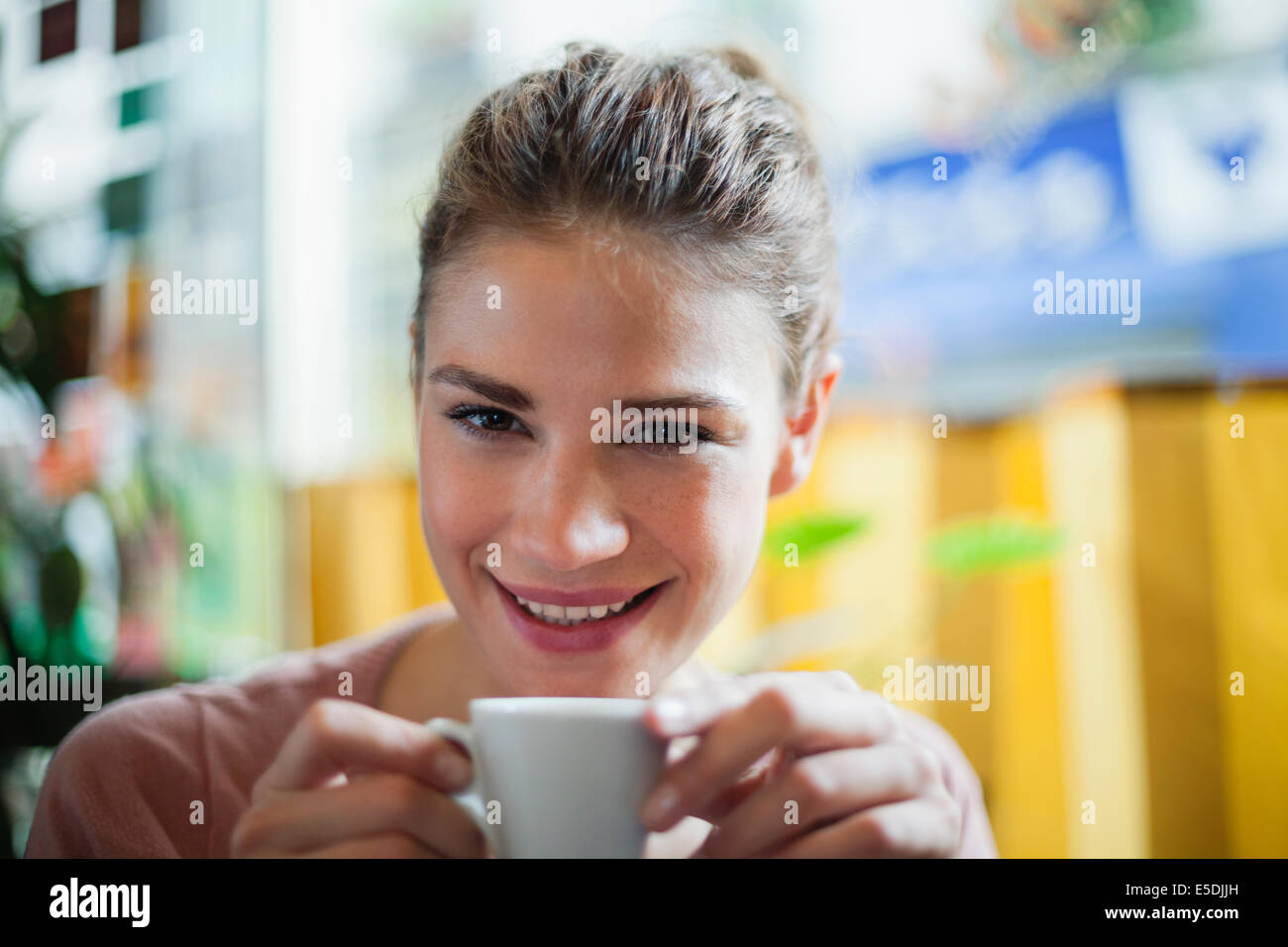 France, Paris, portrait of young woman drinking cup of coffee in a cafe