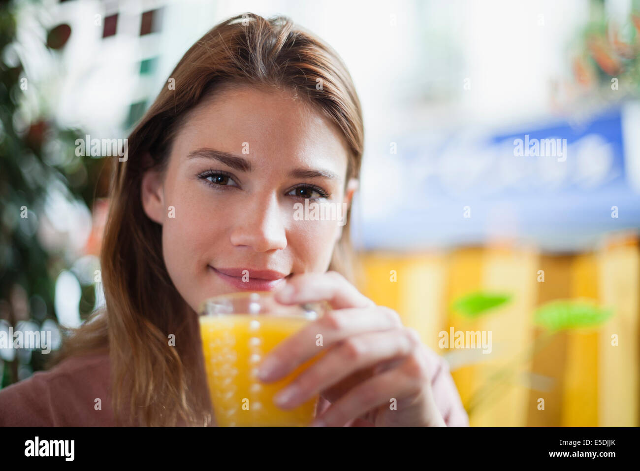 France, Paris, portrait of young woman drinking a glass of juice in a