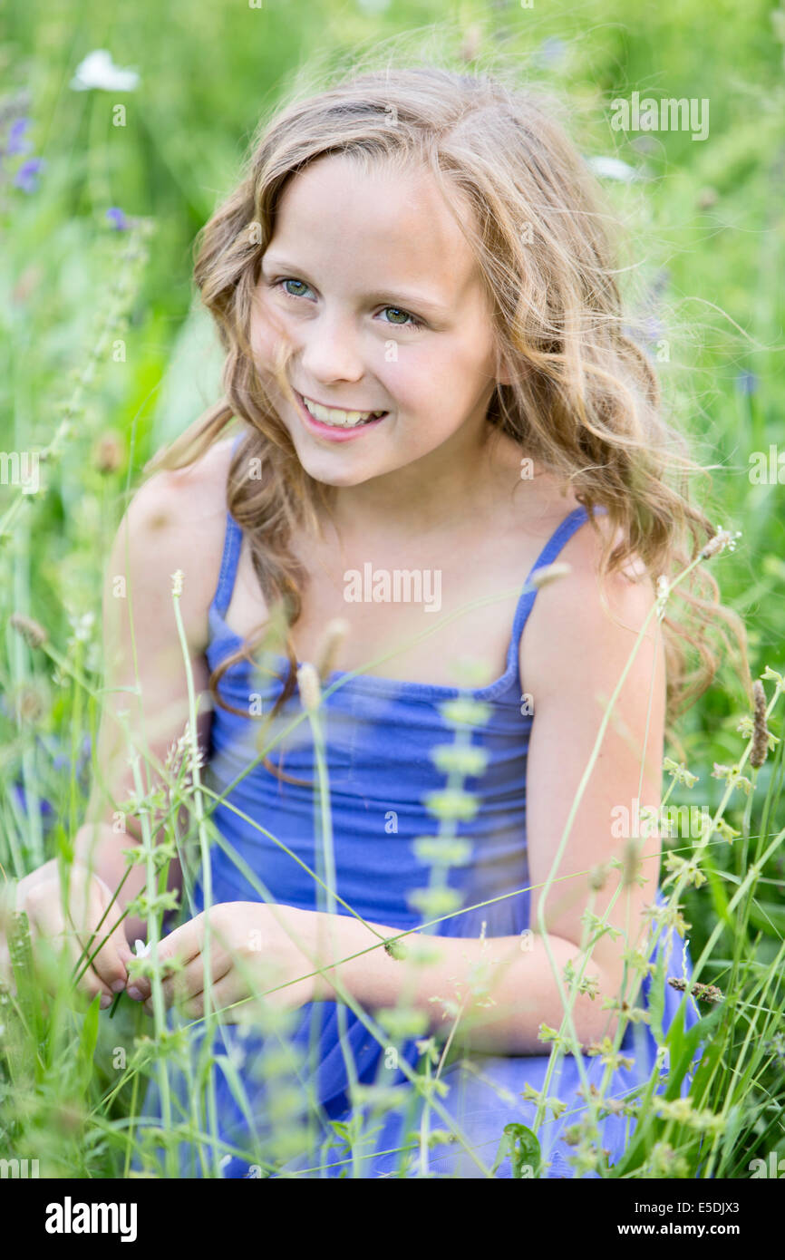 Portrait of smiling girl sitting on flower meadow Stock Photo - Alamy