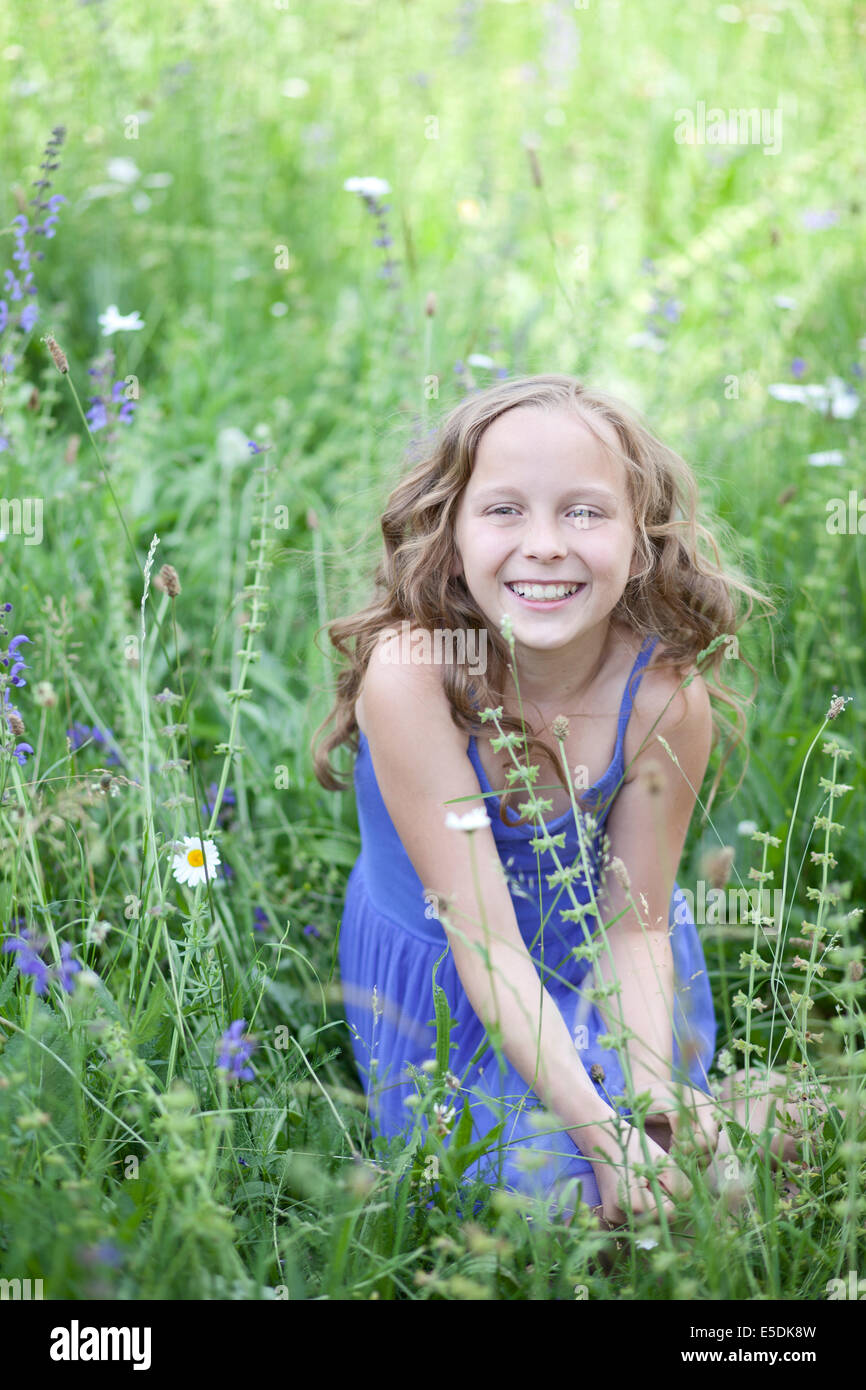 Portrait of smiling girl sitting on flower meadow Stock Photo - Alamy