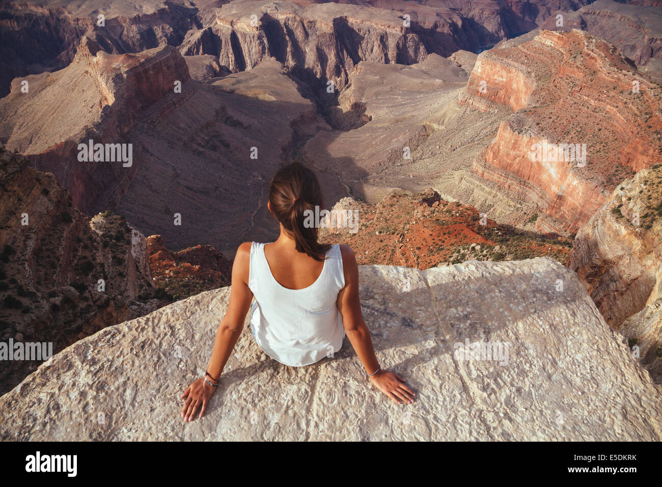 USA, Arizona, woman sitting at cliff of Grand Canyon, back view Stock ...