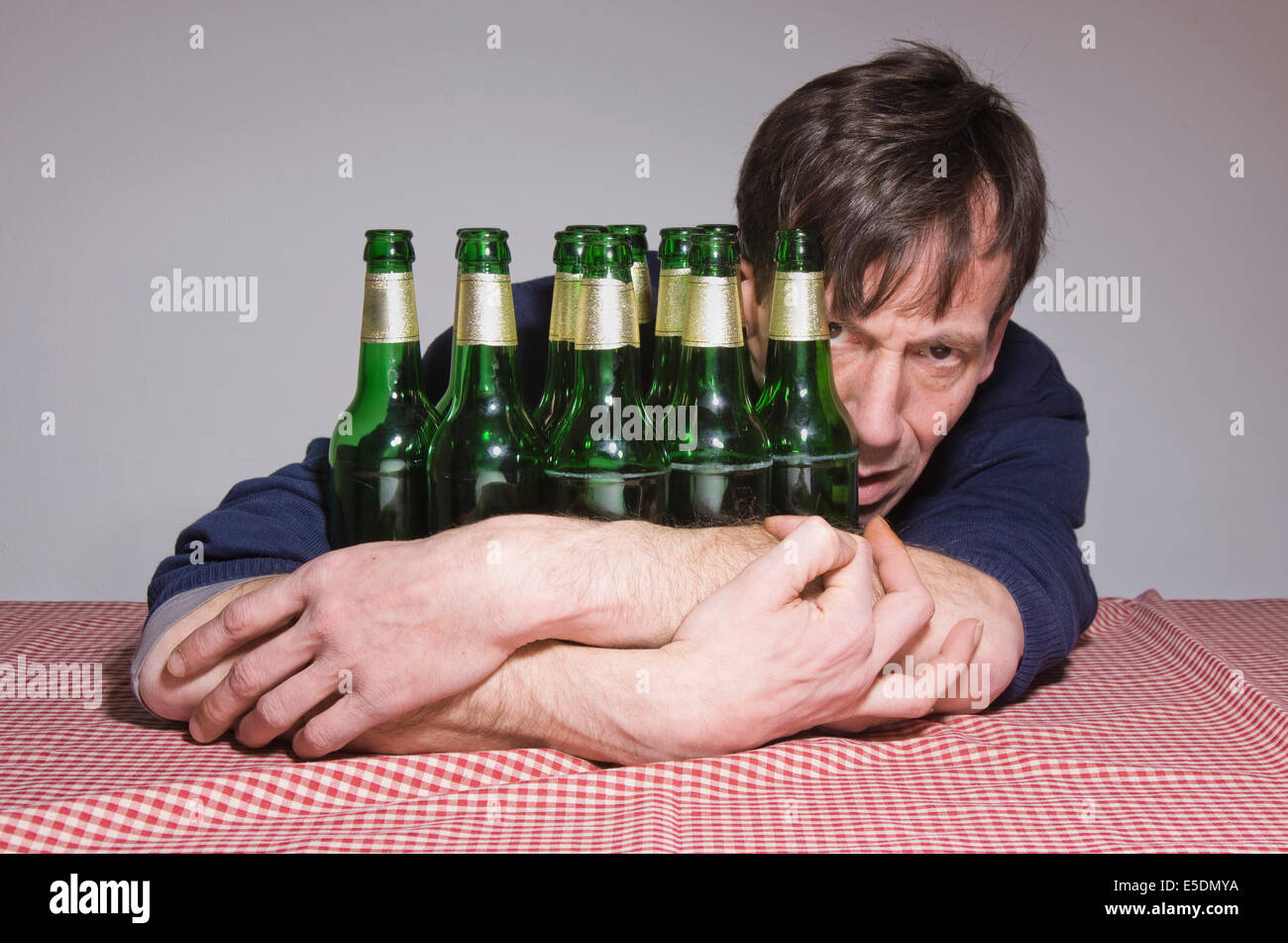Man at table surrounded by beer bottles Stock Photo
